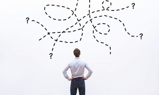 A man looking at a jumbled business strategy on a white wall