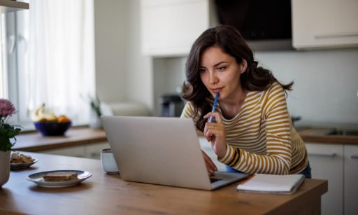 A woman using her laptop to search online for a property management company.