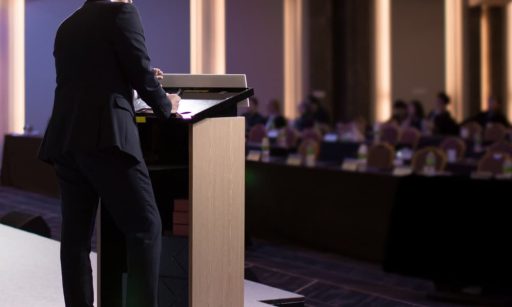 A PM company leader presenting to a crowd of people.