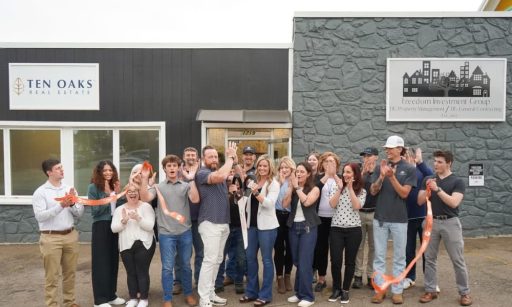 Katie and her husband Clay stand outside of the Ten Oaks Real Estate Management building with their team.