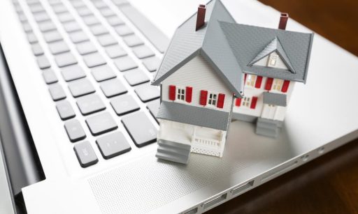 A miniature house sitting on a laptop.
