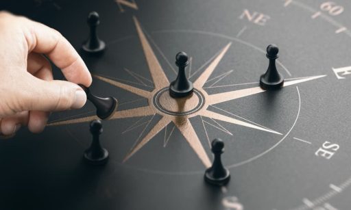 A hand moving chess pieces on a compass design.